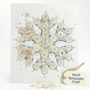 May include: A handmade snowflake art piece crafted from various white and cream-colored buttons, sequins, and beads. The snowflake is centered on a white background, with a light blue outline. The tag reads "8x10 Keepsake Craft".