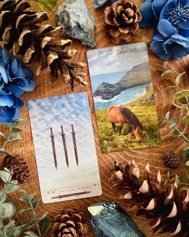 May include: Two tarot cards on a wooden surface surrounded by pine cones and blue flowers. The card on the left is the Four of Swords, depicting three swords standing upright and a fourth sword lying horizontally. The card on the right is the Chariot, showing a horse grazing in a field with a body of water and a cliff in the background.