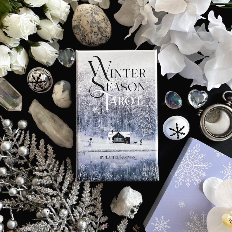 Peut inclure: Une bo&icirc;te blanche avec le texte "Winter Season Tarot" en lettres noires. La bo&icirc;te est entour&eacute;e de fleurs blanches, de cristaux et d'autres objets d&eacute;coratifs.
