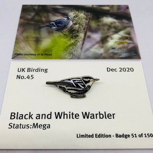 Op de afbeelding: Een zwart-witte emaille pin van een Black and White Warbler, een zeldzame vogel in het Verenigd Koninkrijk. De pin is onderdeel van een gelimiteerde editie, genummerd 51 van de 150. De pin is op een witte kaart met de tekst "UK Birding No.45", "Dec 2020", "Black and White Warbler", "Status: Mega" en "Limited Edition - Badge 51 of 150".
