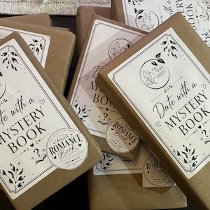 Peut inclure: Plusieurs livres emball&eacute;s avec des &eacute;tiquettes blanches indiquant "Date with a Mystery Book" et "Romance Book". Les livres sont envelopp&eacute;s dans du papier brun. Les &eacute;tiquettes pr&eacute;sentent un motif floral et les mots "The Foliage Goddess".