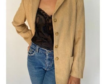 Könnte beinhalten: Ein Blazer in Kamelbraun mit einreihigem Verschluss und vier Knöpfen. Der Blazer hat eine klassische Passform und eine leicht überdimensionierte Silhouette.