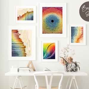 Puede incluir: Un conjunto de cinco impresiones de arte abstracto de colores con una variedad de patrones geométricos y degradados. Las impresiones están enmarcadas en blanco y dispuestas en una pared blanca sobre un escritorio blanco.