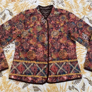 Puede incluir: Una chaqueta acolchada marrón con estampado floral y cuello mandarín. La chaqueta tiene cierre de botón y ribete marrón.