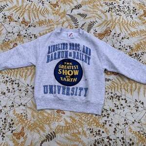 Puede incluir: Sudadera gris con un gráfico azul y blanco del circo Ringling Bros. y Barnum & Bailey. El gráfico dice "The Greatest Show on Earth" y "University".