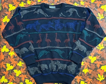 May include: Navy blue sweater with a crew neck and animal patterns. The sweater features rows of kangaroos, horses, flamingos, and bears in various colors, including blue, teal, and burgundy. The cuffs and hem are ribbed.