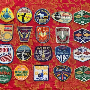 Pode incluir: Uma coleção de patches de boliche vintage em várias formas e cores, incluindo azul, vermelho e dourado. Os patches apresentam textos como "League Champion", "WIBC" e "Bowling Booster", com datas dos anos 1960 a 1980.