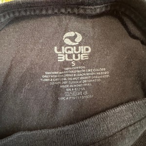 Puede incluir: Una etiqueta de camiseta negra Liquid Blue con texto blanco. La etiqueta dice "Liquid Blue", "S", "100% Algod&oacute;n", "Lavar a m&aacute;quina con agua fr&iacute;a con colores similares", "Usar solo blanqueador sin cloro cuando sea necesario", "Secar en secadora a baja temperatura. No planchar si est&aacute; decorado", "No lavar en seco si est&aacute; decorado", "Hecho en Honduras", "RN#1756", y "UPC #770151339758".
