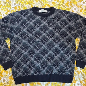 May include: A black and gray sweater with a diamond pattern. The sweater has a crew neck and long sleeves.