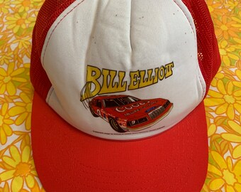 May include: Red and white mesh trucker hat with a red bill. The hat features a graphic of a race car with the text "Bill Elliot" in yellow letters.