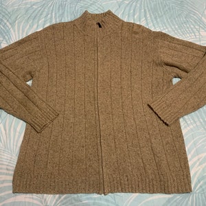 May include: A brown ribbed knit cardigan with a zipper closure. The cardigan has a mock neck and long sleeves.