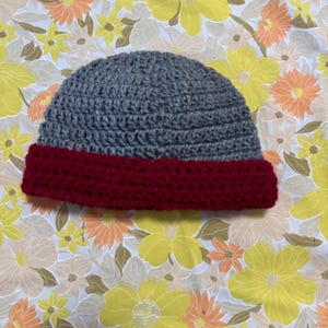 Puede incluir: Gorro de punto gris con borde de punto rojo.
