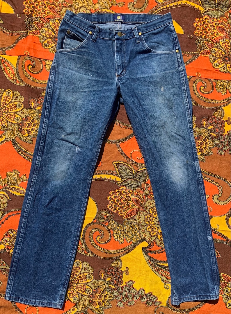 Puede incluir: Un par de pantalones vaqueros azules de mezclilla con un aspecto descolorido y una etiqueta 471 en la parte posterior de la cintura.