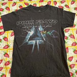 Puede incluir: Camiseta negra con una impresi&oacute;n gr&aacute;fica de la portada del &aacute;lbum "The Dark Side of the Moon" de Pink Floyd.
