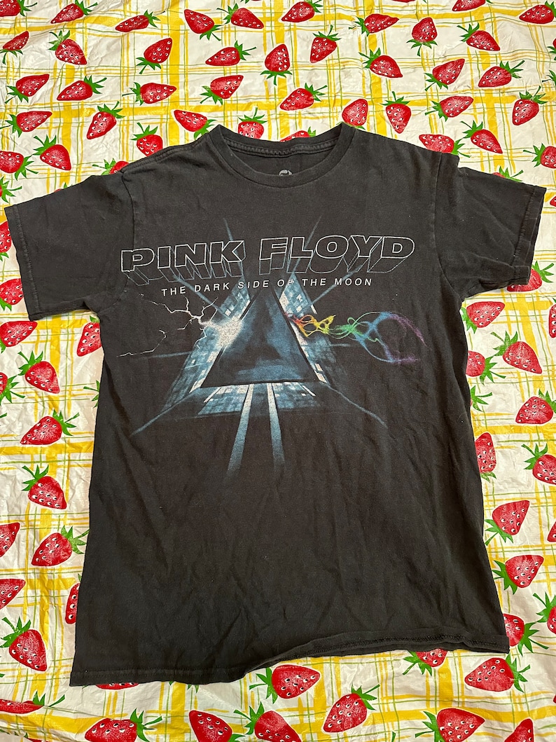 Puede incluir: Camiseta negra con una impresi&oacute;n gr&aacute;fica de la portada del &aacute;lbum "The Dark Side of the Moon" de Pink Floyd.