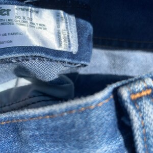 Puede incluir: Primer plano de una etiqueta de mezclilla azul con texto blanco que dice "Wrangler 47MW 4PW 30 X 32", "Lavar a m&aacute;quina con agua fr&iacute;a con colores similares, solo blanqueador sin cloro cuando sea necesario, secar en secadora a baja temperatura, secar en l&iacute;nea", "Hecho en M&eacute;xico con tela de EE. UU., 100 % algod&oacute;n, exclusivo de la decoraci&oacute;n".
