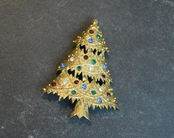 May include: A gold-tone Christmas tree brooch with red, blue, and green rhinestones.