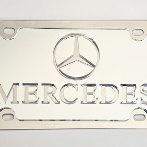 May include: A white ceramic mug with a black handle and the text "But First, Coffee" in a bold, black font. The mug is set against a neutral background, highlighting its simple design.