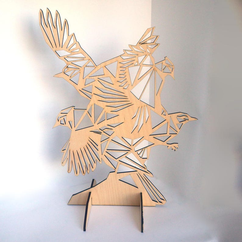 Puede incluir: Una escultura de madera de tres p&aacute;jaros en vuelo, cada p&aacute;jaro est&aacute; hecho de formas geom&eacute;tricas y est&aacute; intrincadamente recortado. Los p&aacute;jaros est&aacute;n montados sobre una base de madera.