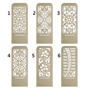 Puede incluir: Seis dise&ntilde;os diferentes para soportes de tel&eacute;fono de madera cortados con l&aacute;ser. Cada soporte presenta un patr&oacute;n geom&eacute;trico &uacute;nico en blanco sobre un fondo marr&oacute;n. Los soportes est&aacute;n numerados del 1 al 6.