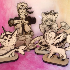 Può includere: Sagome in legno di personaggi di anime e Pokémon, tra cui Naruto, Vaporeon e Leafeon. Ogni figura è tagliata al laser con contorni dettagliati e montata su una piccola base rotonda. Le figure non sono dipinte, mostrando la venatura naturale del legno.