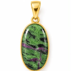 May include: An oval pendant featuring a polished green, black and magenta stone set in a smooth gold-toned metal frame. The pendant includes a matching gold-toned bail at the top, designed for attachment to a necklace chain or cord.