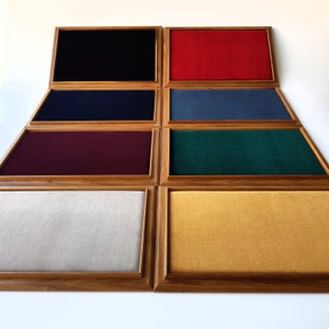 Puede incluir: Una colección de ocho vitrinas de madera, cada una con un interior de tela de diferente color. Los colores incluyen negro, rojo, azul marino, azul, burdeos, verde, blanco roto y dorado. Los marcos son de madera clara.