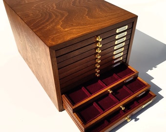 Op de afbeelding: Een houten doos met 10 laden en twee uittrekbare trays. De laden hebben messingknoppen en zijn gelabeld met witte papieren labels. De trays zijn bekleed met rood vilt.