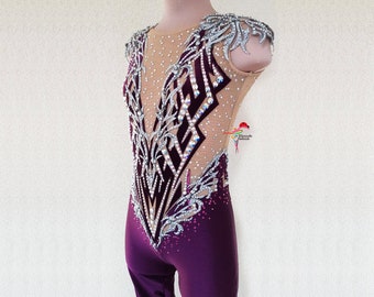 May include: A purple leotard with a silver and black design. The leotard is decorated with rhinestones and has a mesh panel in the front.