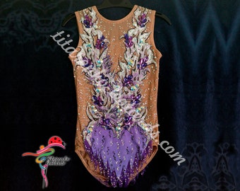 May include: A nude-colored leotard with a purple and white floral design. The leotard is decorated with rhinestones and has a purple fringe at the bottom.