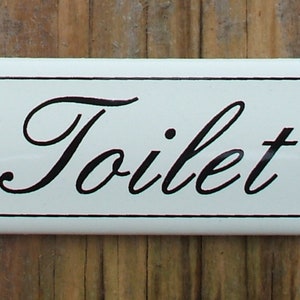 Enseigne classique de toilettes en émail. Texte noir sur fond crème. 12x3cm.