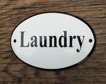 May include: White oval sign with a black border and the word "Laundry" in black lettering.