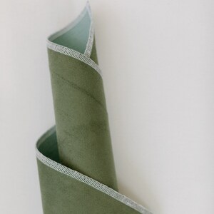 May include: A rolled up piece of green fabric with a white stitched edge.