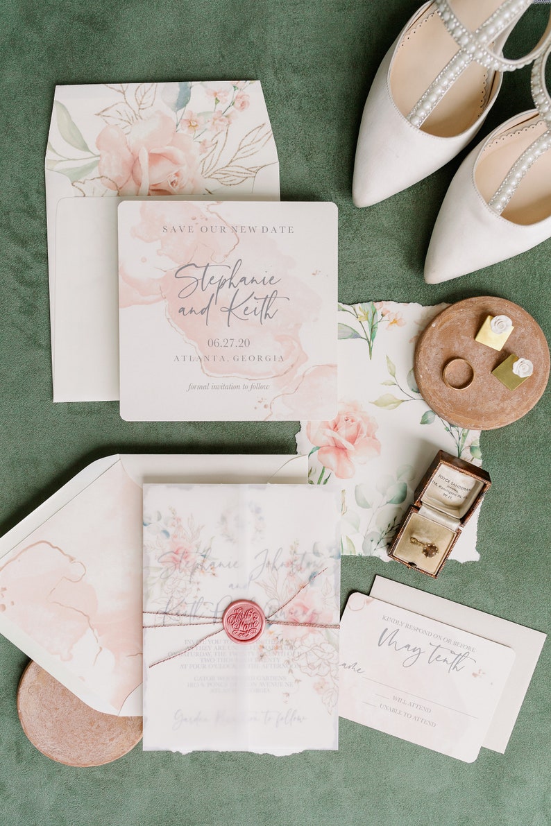 May include: A wedding invitation suite with a watercolor floral design. The invitation card features a pink and white watercolor background with the text "Save Our New Date" and the couple's names, "Stephanie and Keith". The date, "06.27.20", and location, "Atlanta, Georgia", are also included. The RSVP card features the text "Kindly respond on or before May tenth" and options to indicate whether the guest will attend or not.