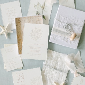 May include: Wedding invitation suite with a beach theme. The invitation features a white coral design and the text "ANALISE and WARREN". The RSVP card has a list of wedding details. The save the date card has the date "10.18.20" and a coral design.