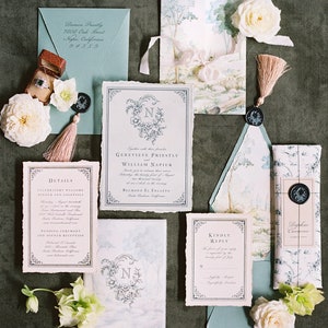 May include: Wedding invitation suite with a watercolor design featuring a forest scene. The invitations are printed on textured paper with a delicate, hand-torn edge. The suite includes a save-the-date card, a wedding invitation, a details card, and a RSVP card. The invitations are decorated with a floral motif and a wax seal.