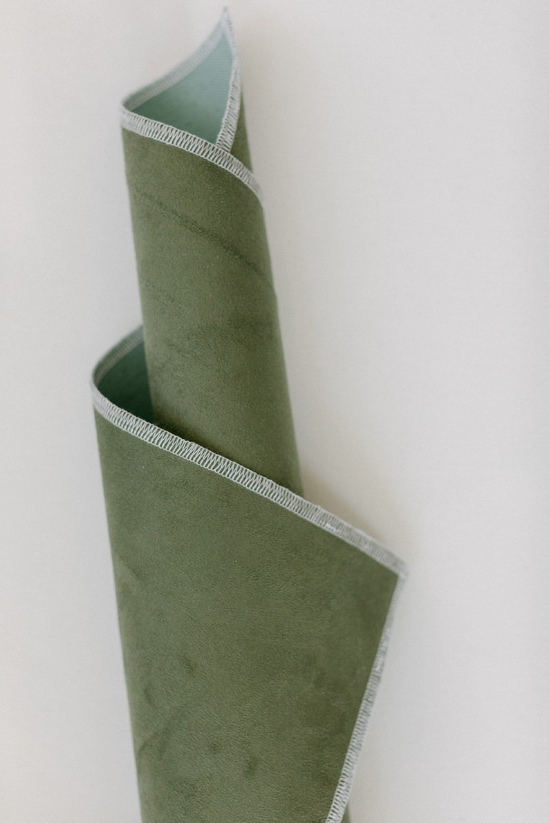 May include: A rolled up piece of green fabric with a white stitched edge.