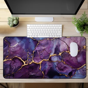 Può includere: Tappetino per mouse con motivo marmoreo viola e oro con un mouse bianco in cima. Il tappetino per mouse ha un design screpolato, astratto con venature dorate.