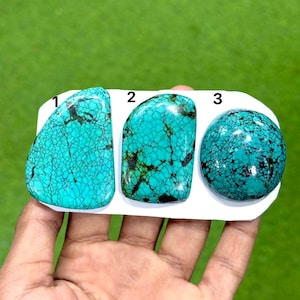 Puede incluir: Tres piedras preciosas de turquesa pulida etiquetadas 1, 2 y 3. Las piedras son de un cian vibrante con intrincados patrones de matriz negra. La piedra 1 es triangular, la 2 es rectangular con bordes redondeados y la 3 es circular.