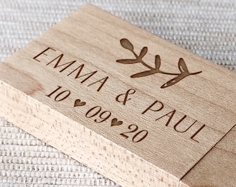 Op de afbeelding: Een houten USB-stick met de tekst "Emma & Paul 10.09.20" en een klein bloemetjespatroon.