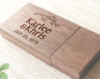 Op de afbeelding: Een houten USB-stick met een gepersonaliseerde inscriptie die "Karlee & Chris July 20, 2019" luidt. De inscriptie is in een bruin lettertype en bevat een klein bloemenmotief.