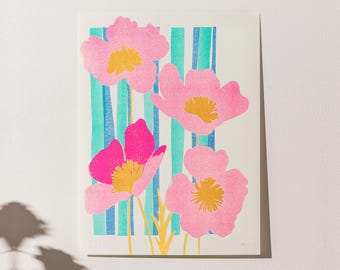 May include: A print of pink flowers with yellow centers on a background of blue and green stripes.