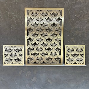 May include: Three Art Deco-style brass panels with a fan-shaped design. The largest panel is rectangular, while the other two are square. The panels are displayed on a white shelf against a dark gray textured wall.