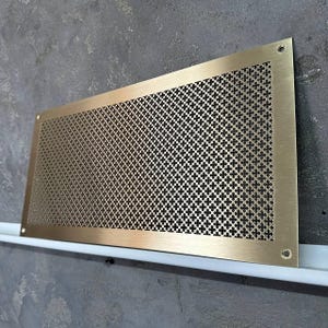 May include: A gold metal vent cover with a decorative, repeating pattern of small, four-leaf clover shapes.