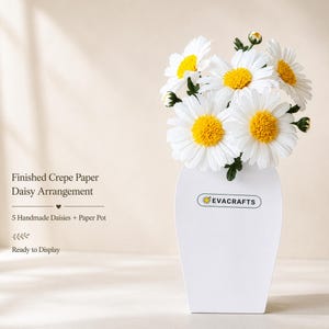 Puede incluir: Un ramo de cinco margaritas de papel crepé blanco con centros amarillos en una maceta de papel blanca. La maceta muestra el texto EVACRAFTS. El texto a la izquierda dice: Finished Crepe Paper Daisy Arrangement, 5 Handmade Daisies + Paper Pot, Ready to Display.