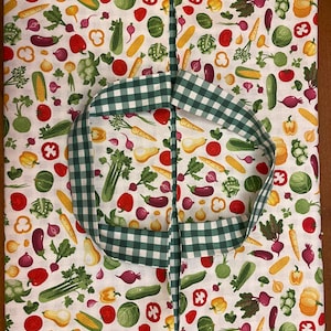 Peut inclure: Un sac fourre-tout en tissu blanc avec une poignée en vichy vert et blanc. Le sac est imprimé d'un motif de différents légumes, dont des carottes, des oignons, des poivrons et des concombres.