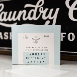 Puede incluir: Una caja azul de 64 hojas de detergente para la ropa con el texto "Fresh Breeze" y "Eco Roots" en la parte delantera. La caja tambi&eacute;n dice "Hipoalerg&eacute;nico, ecol&oacute;gico y ultraconcentrado" y "Hojas de detergente para la ropa".