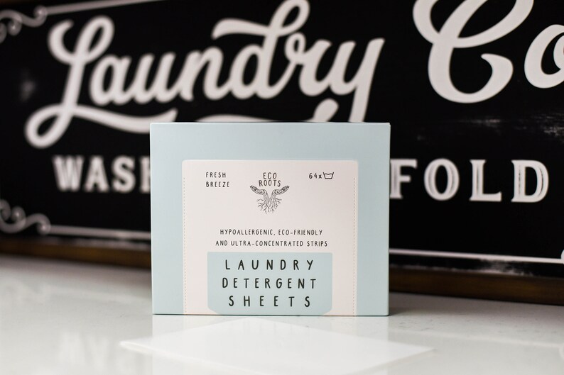 Puede incluir: Una caja azul de 64 hojas de detergente para la ropa con el texto "Fresh Breeze" y "Eco Roots" en la parte delantera. La caja tambi&eacute;n dice "Hipoalerg&eacute;nico, ecol&oacute;gico y ultraconcentrado" y "Hojas de detergente para la ropa".