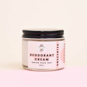 May include: A white jar with a black lid containing unscented deodorant cream. The label reads "Eco Roots Deodorant Cream Baking Soda Free 2 oz Unscented".
