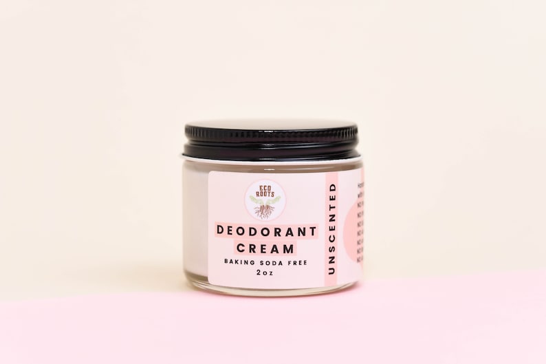 May include: A white jar with a black lid containing unscented deodorant cream. The label reads "Eco Roots Deodorant Cream Baking Soda Free 2 oz Unscented".